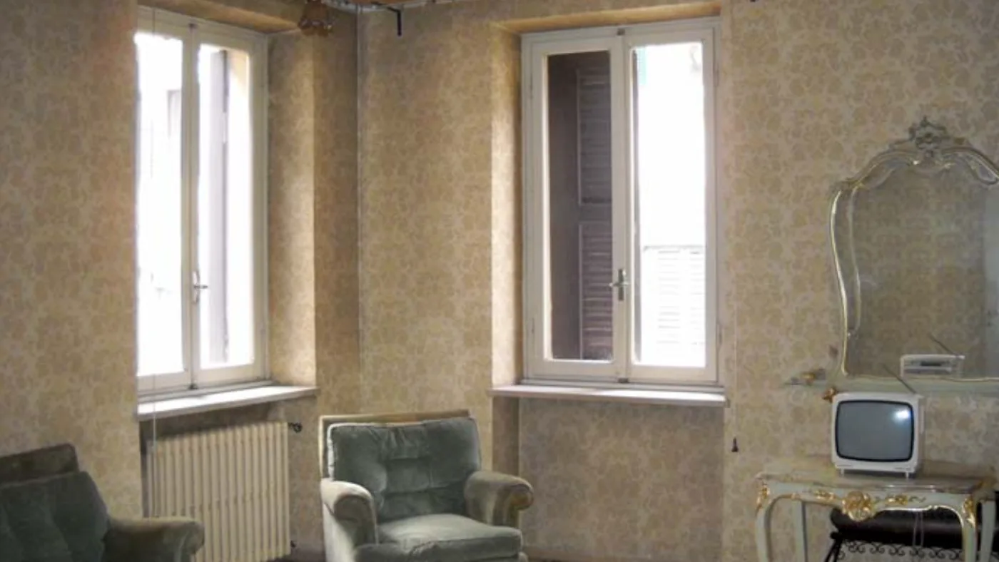 Loft FB before the works — the original living room with patterned wallpaper and terrazzo floor