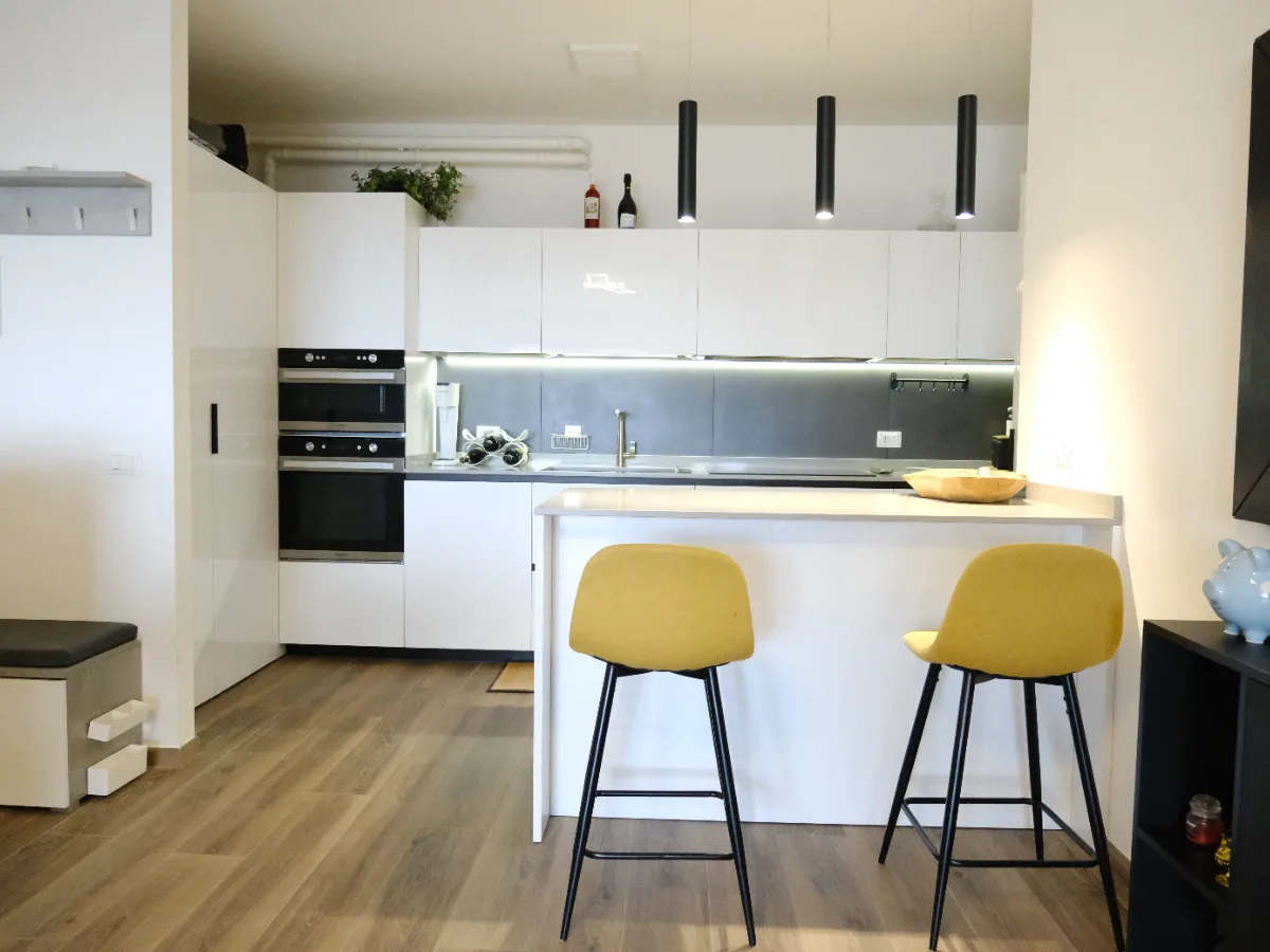 Attico SB, Verona — the finished kitchen with its island and yellow stools